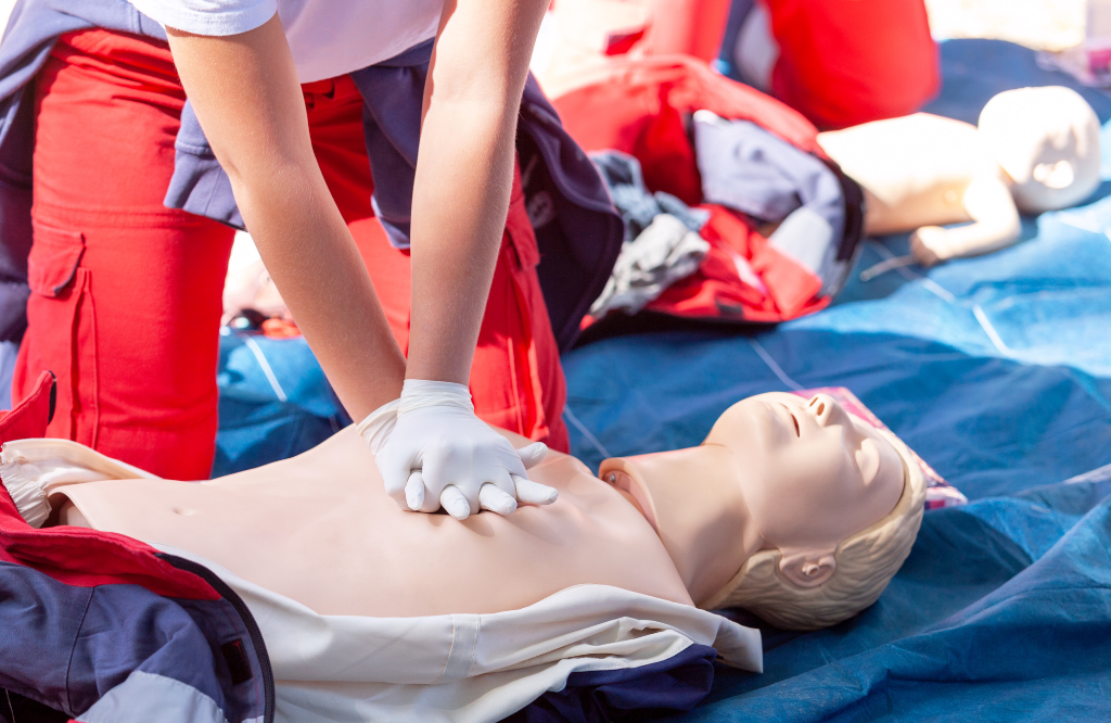 A woman performing CPR on a dummy during a first-aid course