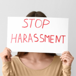 Woman holding up a stop harassment sign for the new sexual harassment in the workplace laws