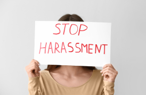 Woman holding up a stop harassment sign for the new sexual harassment in the workplace laws