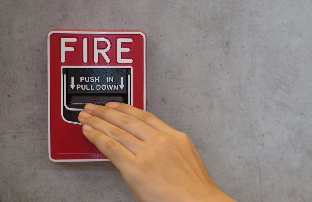 A man pressing down the fire alarm