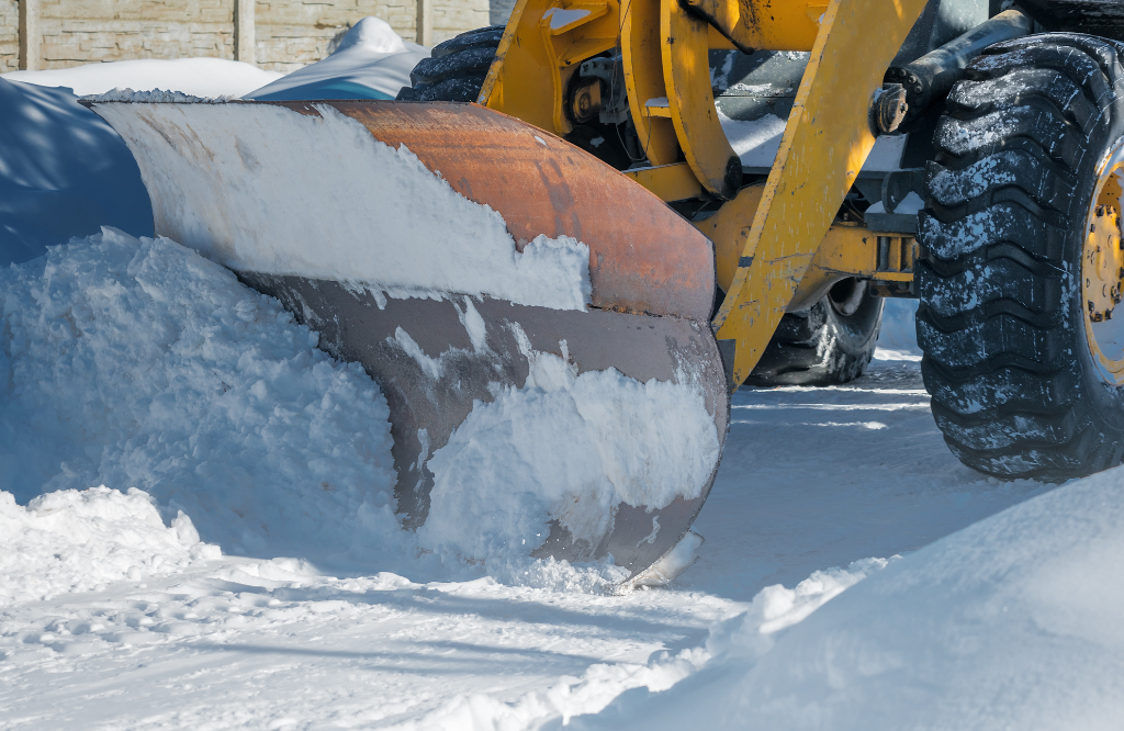 A digger in the snow shovelling the snow away from the construction site