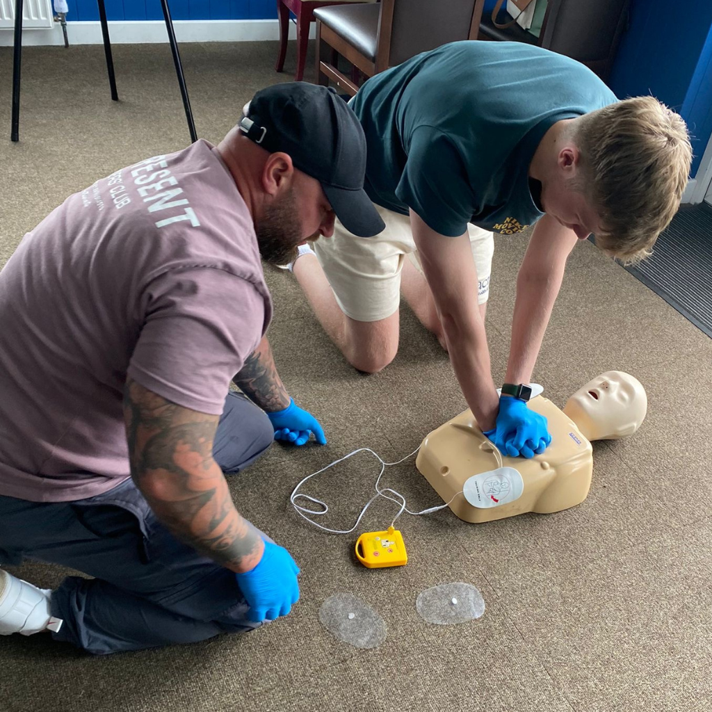 Two men learning CPR while training to be first aiders