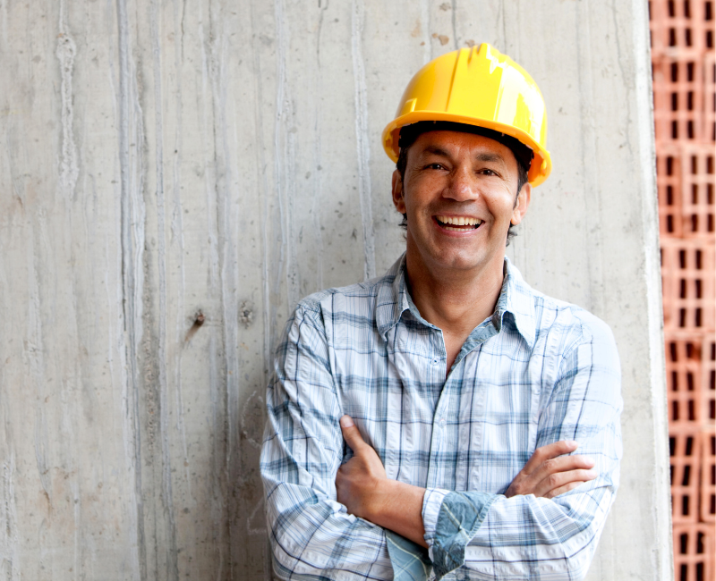 A construction worker smiling because of his retained health and safety service