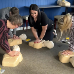 Four employees in a circle learning how to perform CPR