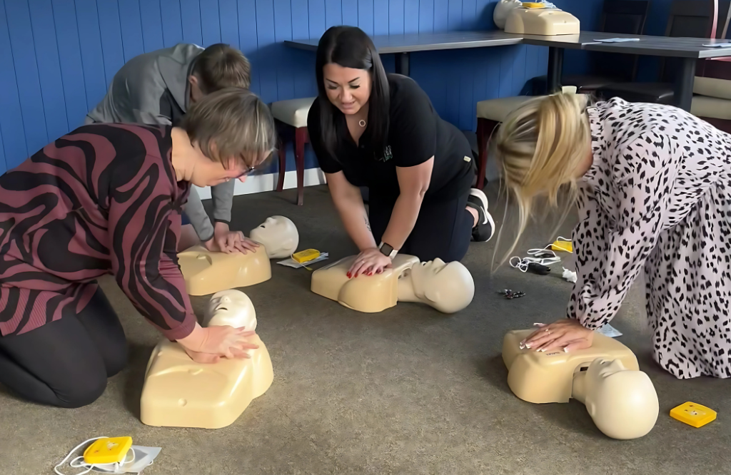 Four employees in a circle learning how to perform CPR