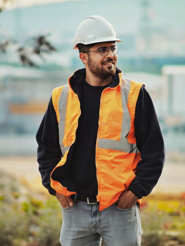 Construction worker wearing PPE including hard hat and high-visibility vest on a UK building site
