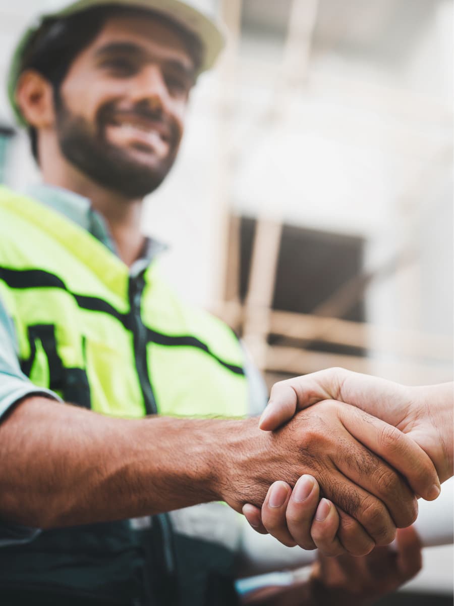 Construction professional in high-visibility PPE shaking hands on a UK construction site
