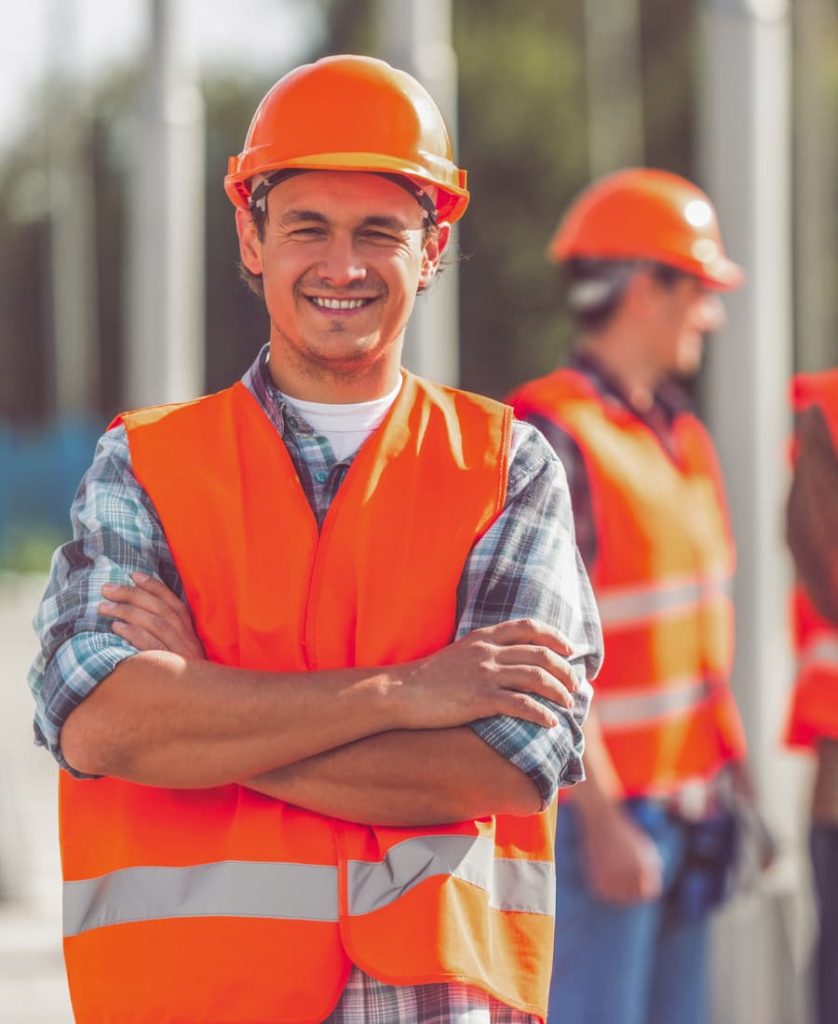 Construction worker wearing orange high-visibility vest and hard hat on a UK construction site